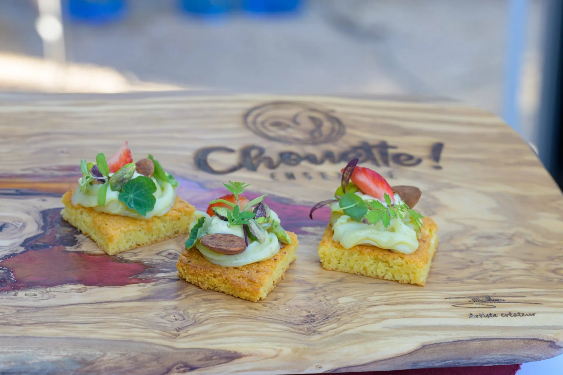 Bouchées apéritives dressées sur une planche en bois gravée du logo Chouette
